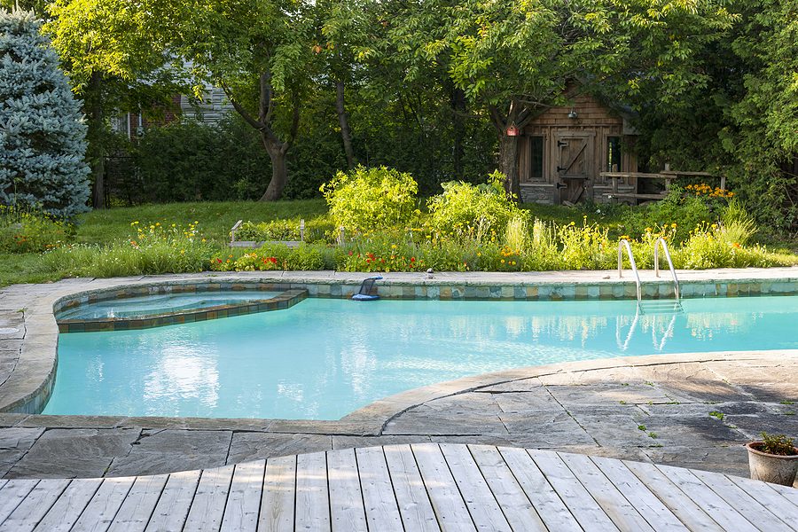 inground swimming pool with a brick and wood floor